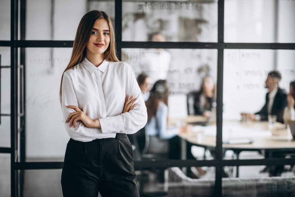 smiling woman standing outside a conference room for free transcriptions